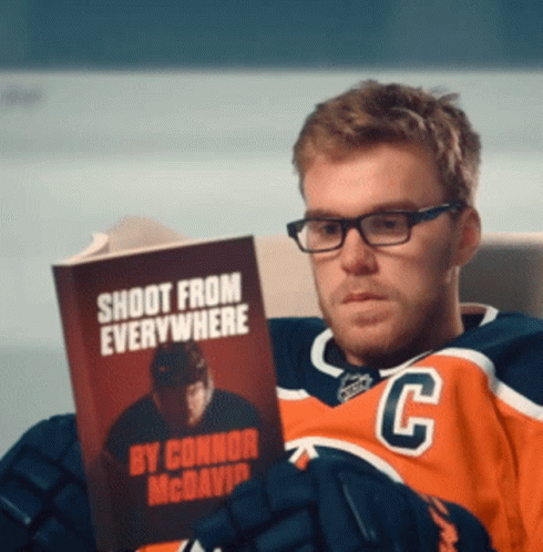 A Hockey Player Reading A Book Called Shoot From Everywhere GIF