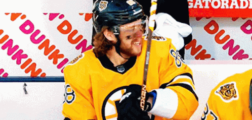 A Hockey Player Stands In Front Of A Dunkin ' Donuts Sign GIF
