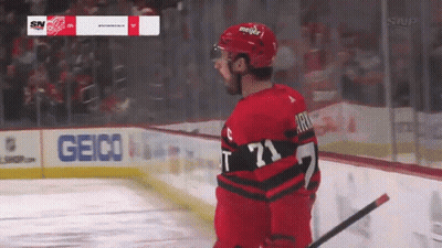 A Hockey Player Stands On The Ice With A Geico Sign In The Background GIF