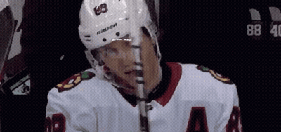 A Hockey Player Wearing A Bauer Helmet Is Holding A Hockey Stick GIF