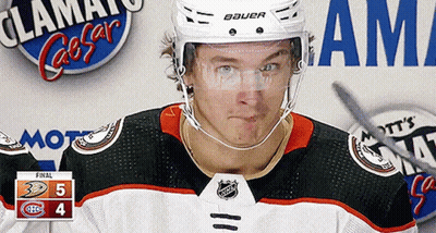 A Hockey Player Wearing A Bauer Helmet Stands In Front Of A Scoreboard GIF