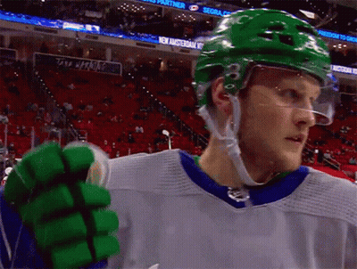 A Hockey Player Wearing A Green Helmet Stands In Front Of A Sign That Says Sega GIF