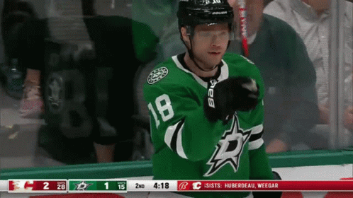 A Hockey Player Wearing A Green Number 18 Jersey GIF