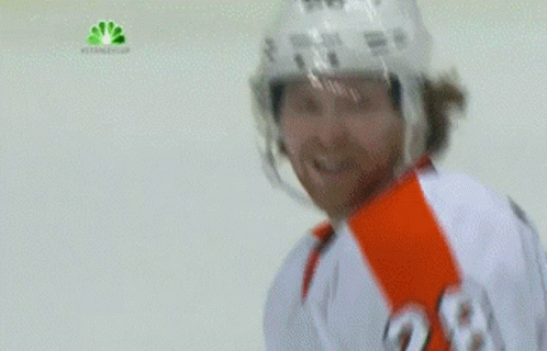 A Hockey Player Wearing A Helmet And A White Jersey Is Smiling GIF
