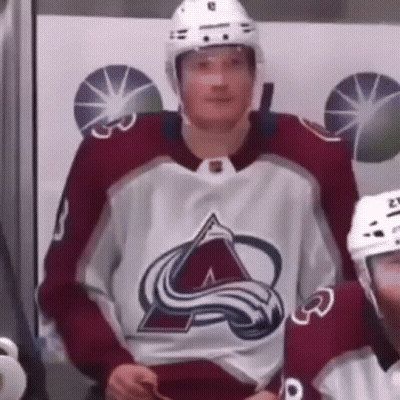 A Hockey Player Wearing A Red And White Jersey And A Helmet Is Sitting In The Stands . GIF