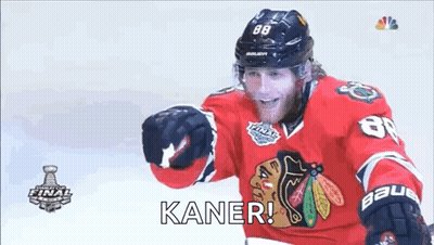 A Hockey Player Wearing A Red Jersey And A Black Helmet Is Standing On The Ice And Smiling . GIF