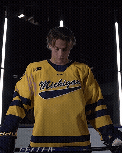 A Hockey Player Wearing A Yellow Michigan Jersey GIF