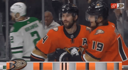 A Hockey Player With A 19 On His Jersey Stands Next To Another Player GIF
