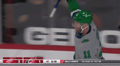 A Hockey Player With The Number 11 On His Jersey Is Holding A Stick In The Air GIF