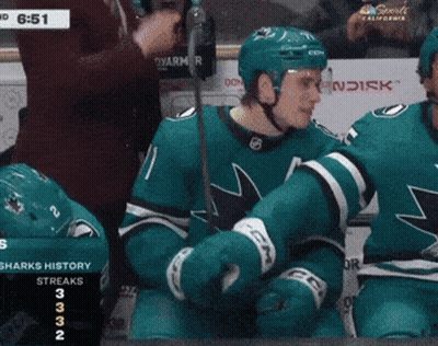A Hockey Player With The Number 11 On His Jersey Stands In Front Of A Scoreboard GIF