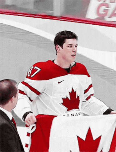 A Hockey Player With The Number 87 On His Jersey Is Holding A Canadian Flag GIF