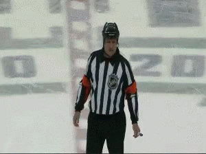 A Hockey Referee Stands On The Ice In Front Of A Sign That Says ' O'zd ' GIF