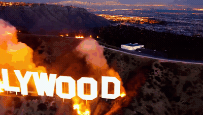 A Hollywood Sign Is On Fire With A City In The Background GIF