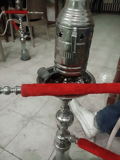 A Hookah With A Red Hose Is Sitting On The Floor GIF