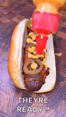 A Hot Dog With Mustard And Jalapenos Is Being Poured On It GIF