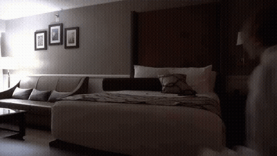 A Hotel Room With A King Size Bed A Couch And A Coffee Table GIF