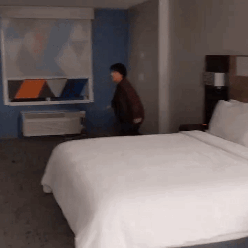 A Hotel Room With A Large Bed And A Window GIF