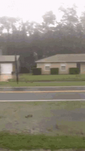 A House Is Sitting On The Side Of The Road Next To A Street . GIF