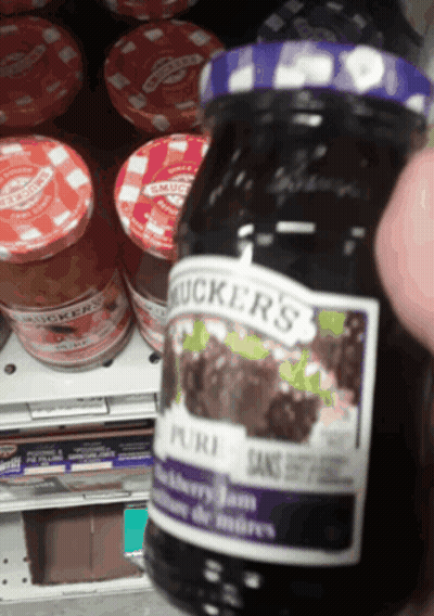 A Jar Of Mucker 'S Blackberry Jam Is Being Held Up GIF