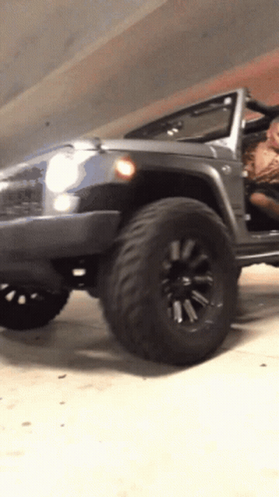 A Jeep Is Parked In A Garage With The Doors Open GIF