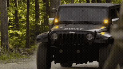 A Jeep With The Word Swat On The Front Is Driving Down A Dirt Road GIF