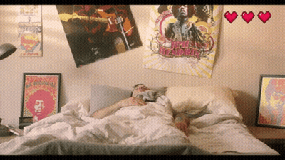 A Jimi Hendrix Poster Hangs On A Wall Above A Man Laying In Bed GIF
