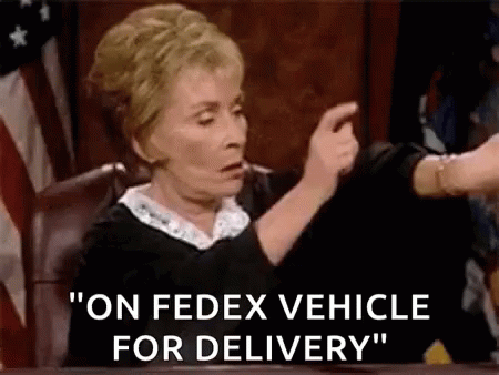 A Judge Is Pointing At A Fedex Vehicle For Delivery While Sitting At A Desk . GIF