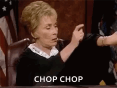 a judge is sitting at a table giving a thumbs up while another judge holds her hand up .