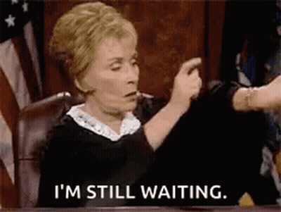 A Judge Is Sitting At A Table In A Courtroom And Says `` I 'M Still Waiting '' . GIF