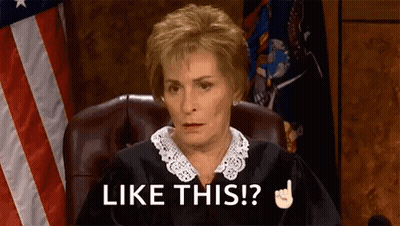 A Judge Is Sitting In A Courtroom With An American Flag In The Background . GIF