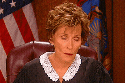 A Judge With Her Eyes Closed Is Sitting In Front Of An American Flag . GIF