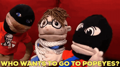 A Kfc Shirt Is On A Puppet With The Words Who Wants To Go To Popeyes Below It GIF