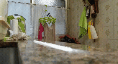 A Kitchen With Clothes Hanging On A Clothes Line GIF