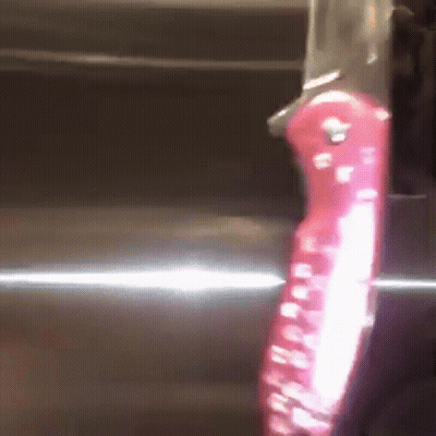 A Knife With A Red Handle Is On A Shiny Surface GIF