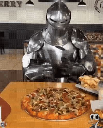 A Knight In Armor Is Sitting At A Table With A Pizza GIF