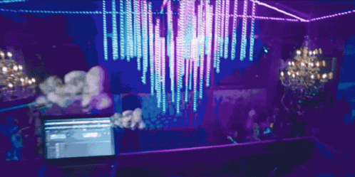 A Laptop Is On A Table In Front Of A Purple Chandelier GIF