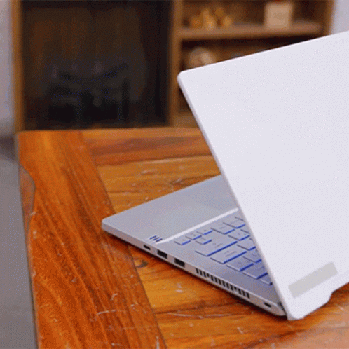 A Laptop Is Open On A Wooden Table GIF
