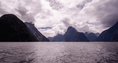 A Large Body Of Water Surrounded By Mountains And A Cloudy Sky GIF