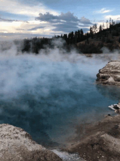 A Large Body Of Water With Trees In The Background And A Lot Of Steam Coming Out Of It GIF