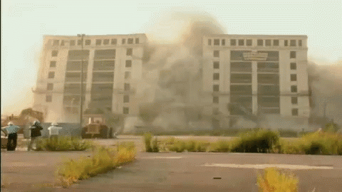A Large Building Is Being Demolished And Smoke Is Coming Out Of The Building GIF