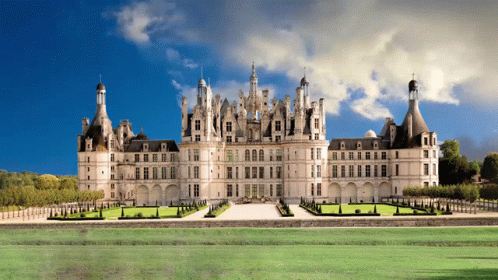 A Large Castle Sits In The Middle Of A Grassy Field GIF