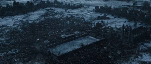 A Large Crowd Of People Are Gathered Around A Large Building In The Middle Of A Snowy Field GIF