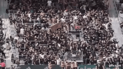 A Large Crowd Of People Are Sitting In A Stadium Watching A Soccer Game . GIF