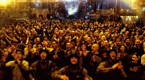 A Large Crowd Of People Are Standing In Front Of A Building That Says ' A ' On It GIF