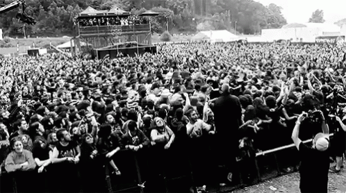 A Large Crowd Of People Are Standing In Front Of A Stage At A Music Festival . GIF