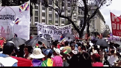 A Large Crowd Of People Holding Umbrellas And A Sign That Says Trabajadores De La Via Publica GIF