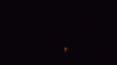 A Large Explosion Of Fire Is Coming Out Of The Ground In The Dark . GIF