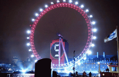 A Large Ferris Wheel Is Lit Up At Night And Has A Clock On It That Says ' E ' On It GIF