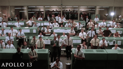A Large Group Of Men Are Gathered In A Room With The Words Apollo 13 On The Bottom Right GIF
