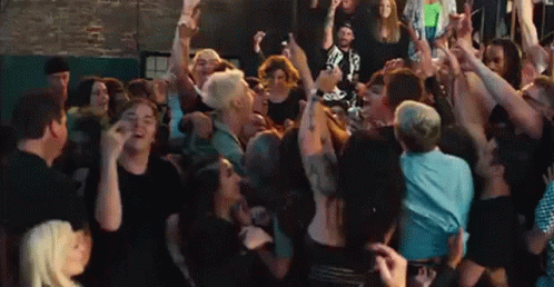 A Large Group Of People Are Dancing In A Crowd At A Concert . GIF